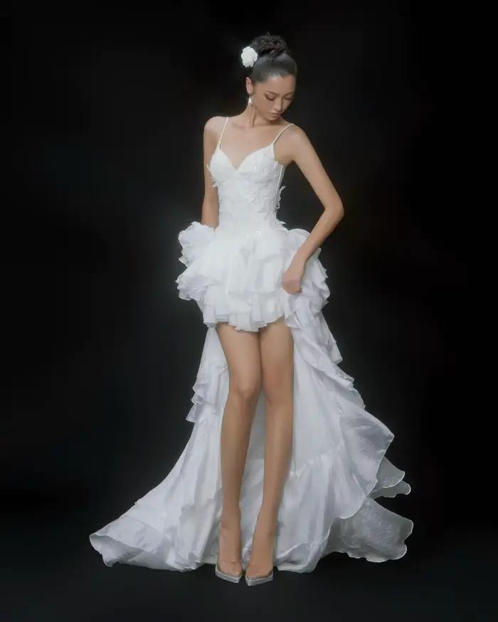 Robe de mariée blanche à ourlet asymétrique avec décolleté en V profond, dentelle et volants, longue